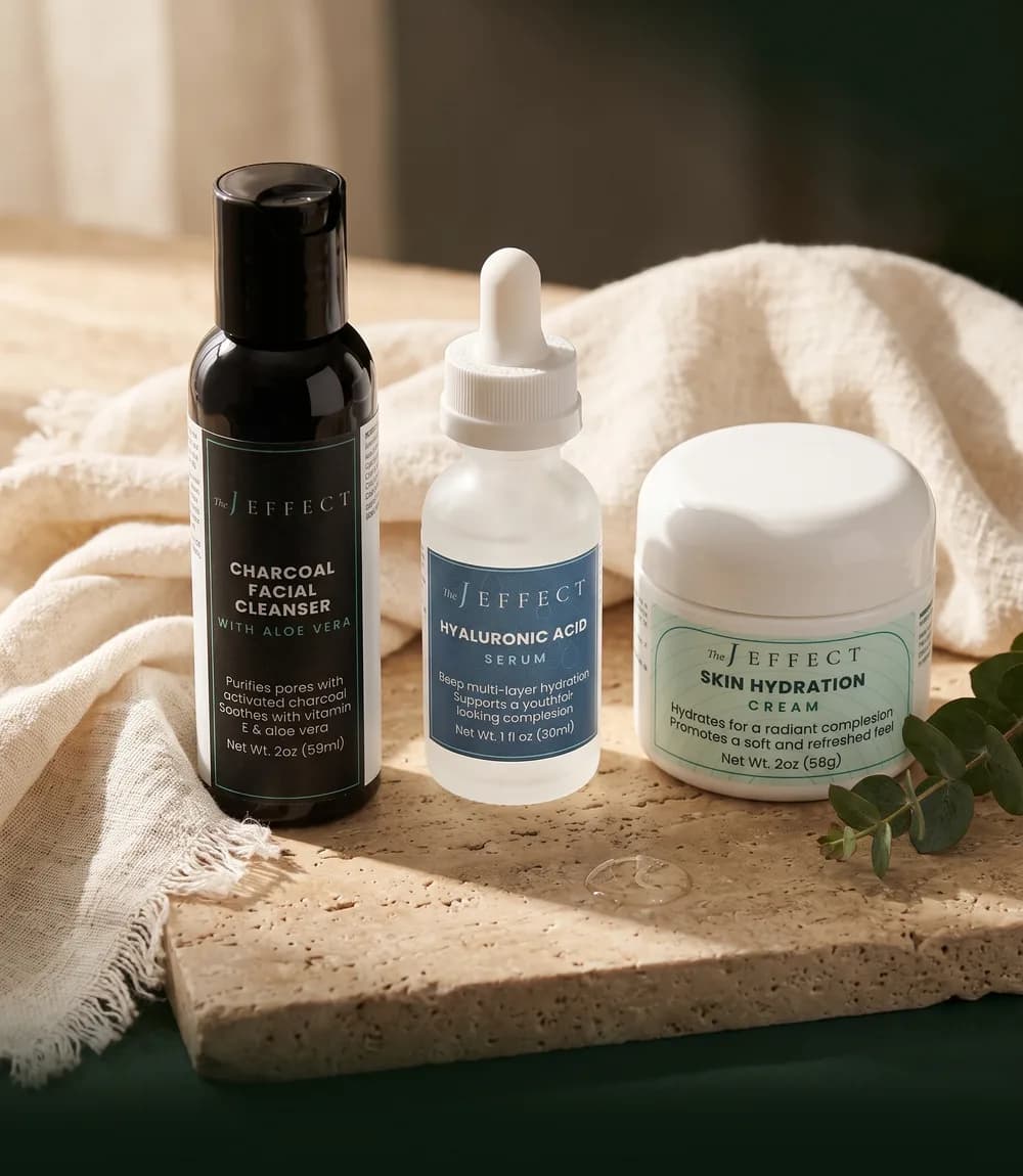 Charcoal cleanser, hyaluronic acid serum and hydration cream on a travertine slab